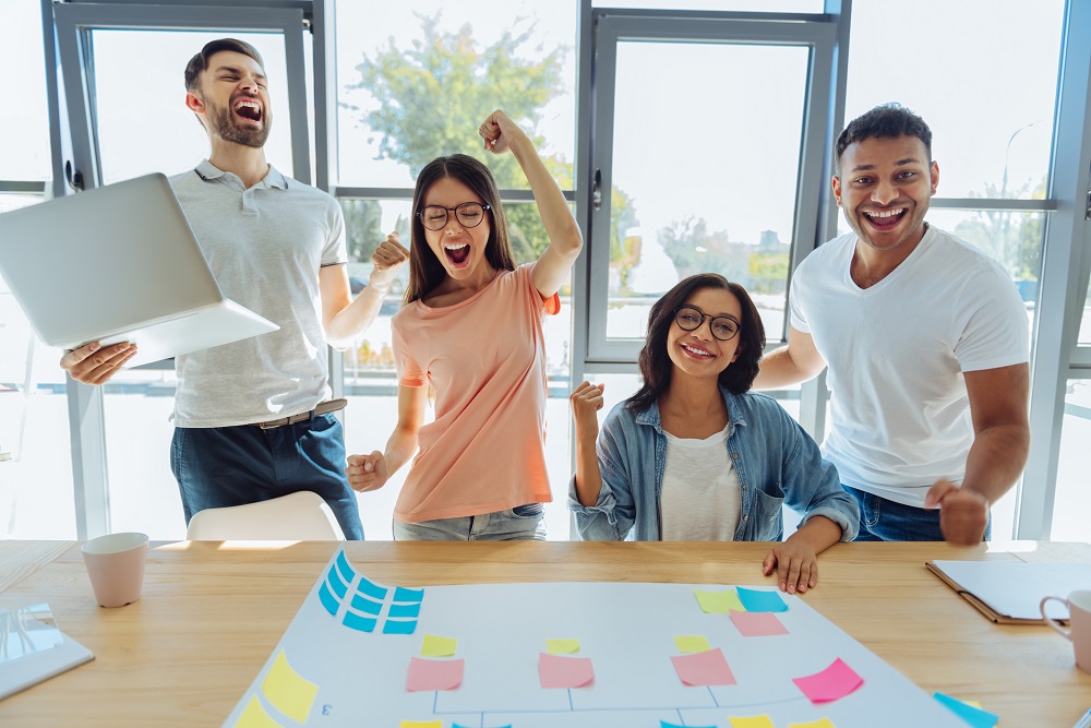 Equipo de emprendedores jóvenes celebran en reunión sobre cómo atraer clientes a su tienda online