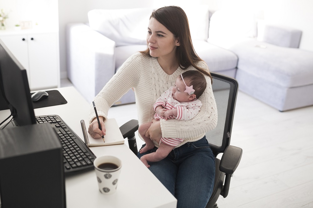 Emprendedora frente a la computadora con una bebé
