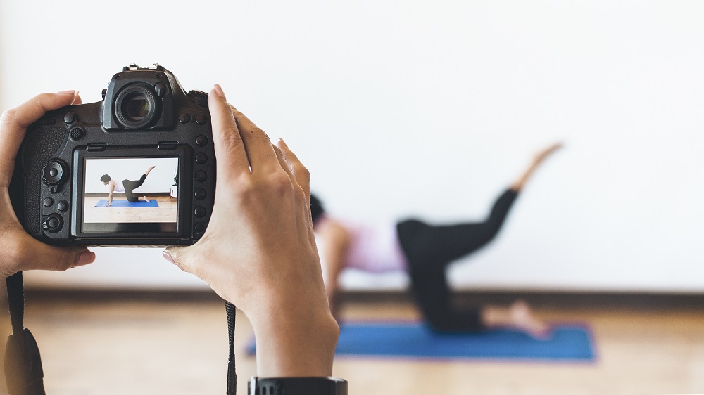 Mujer toma foto a otra que hace yoga como parte de una pieza de publicidades de prodcutos